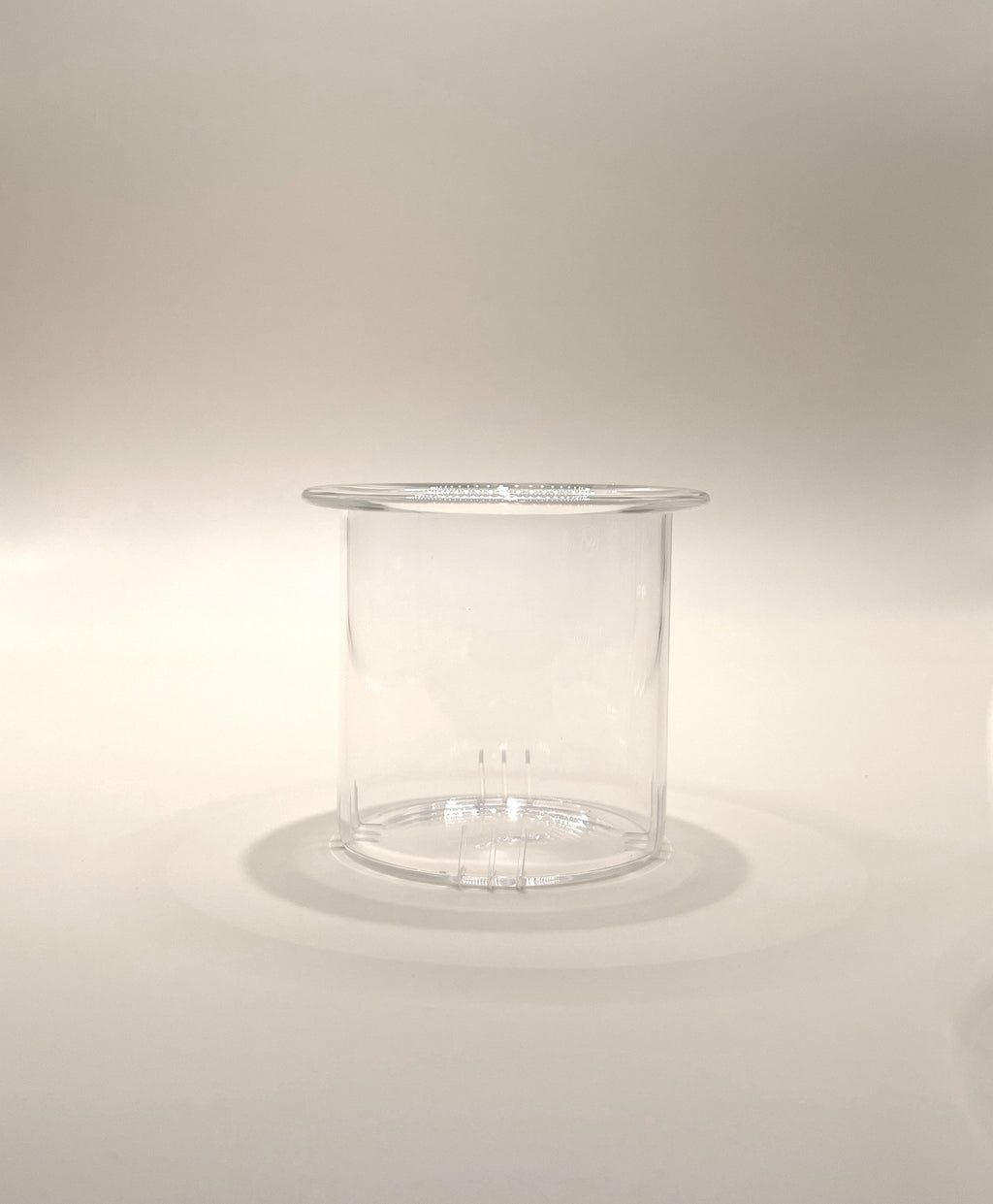 A transparent, cylindrical plastic container with a slightly flared top edge. Reminiscent of the My Store Crystal Clarity Teapot with its pristine appearance, the 600ml container is empty and placed on a neutral, light-colored surface with soft lighting creating subtle shadows.