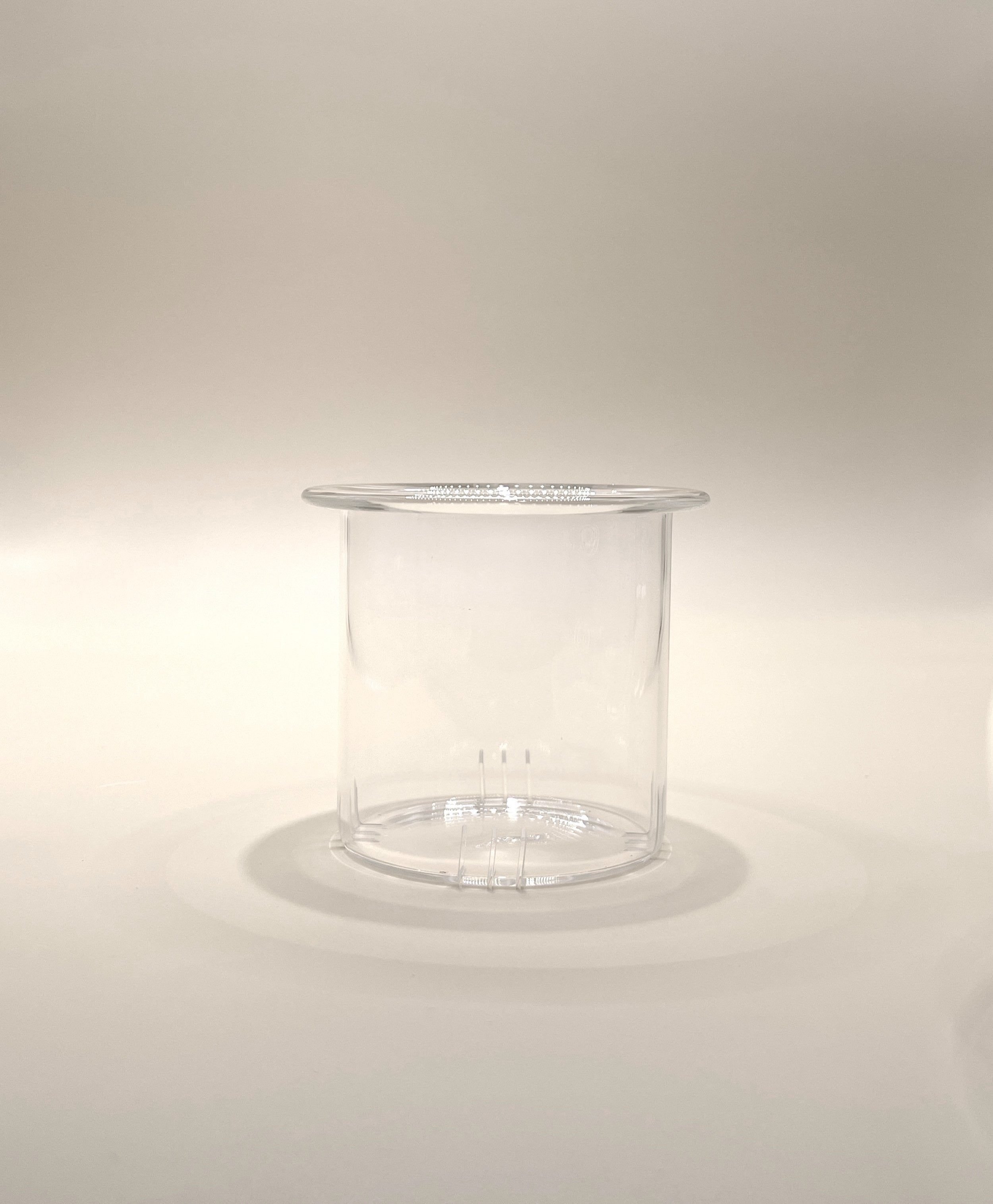 A transparent, cylindrical plastic container with a slightly flared top edge. Reminiscent of the My Store Crystal Clarity Teapot with its pristine appearance, the 600ml container is empty and placed on a neutral, light-colored surface with soft lighting creating subtle shadows.