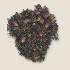 Cocoa Tea by My Store features loose tea leaves mixed with dried rose petals, scattered on a plain, light background. The dark cocoa tea leaves and the pink rose petals create a contrasting and visually appealing blend, rich in antioxidants that support overall well-being.