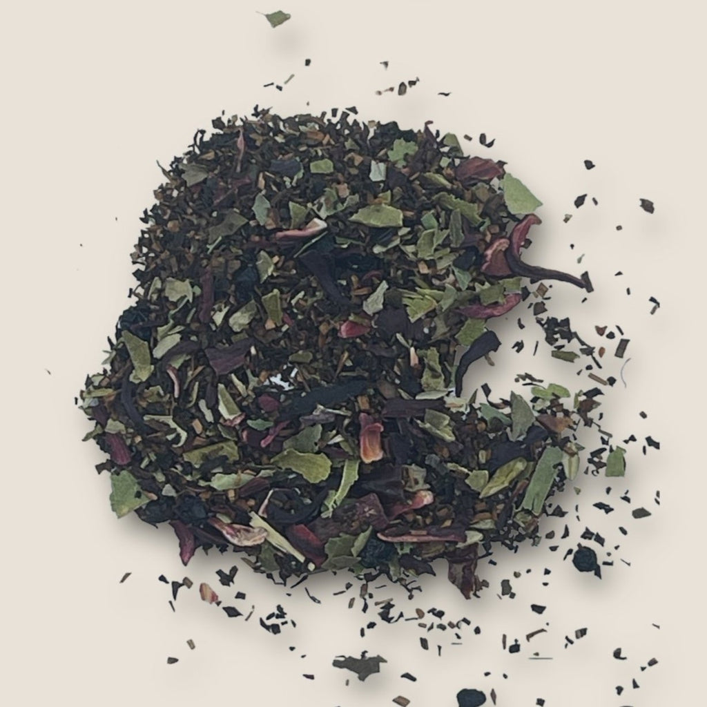 Fairy's Magic Tea by My Store showcases an array of loose tea leaves and herbs, boasting a colorful blend of dark, green, and purple pieces scattered across a light background. The freshly dried tea blend exhibits varied textures and hues, hinting at its diverse ingredients designed for detoxification and immune support.