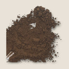 A scattering of finely ground brown powder, identified as My Store's Cocoa Powder, is spread unevenly against a plain cream background. Some clumps are larger, while others are more powdery, giving the texture a varied, earthy appearance with hints of antioxidants known to boost cognitive function.