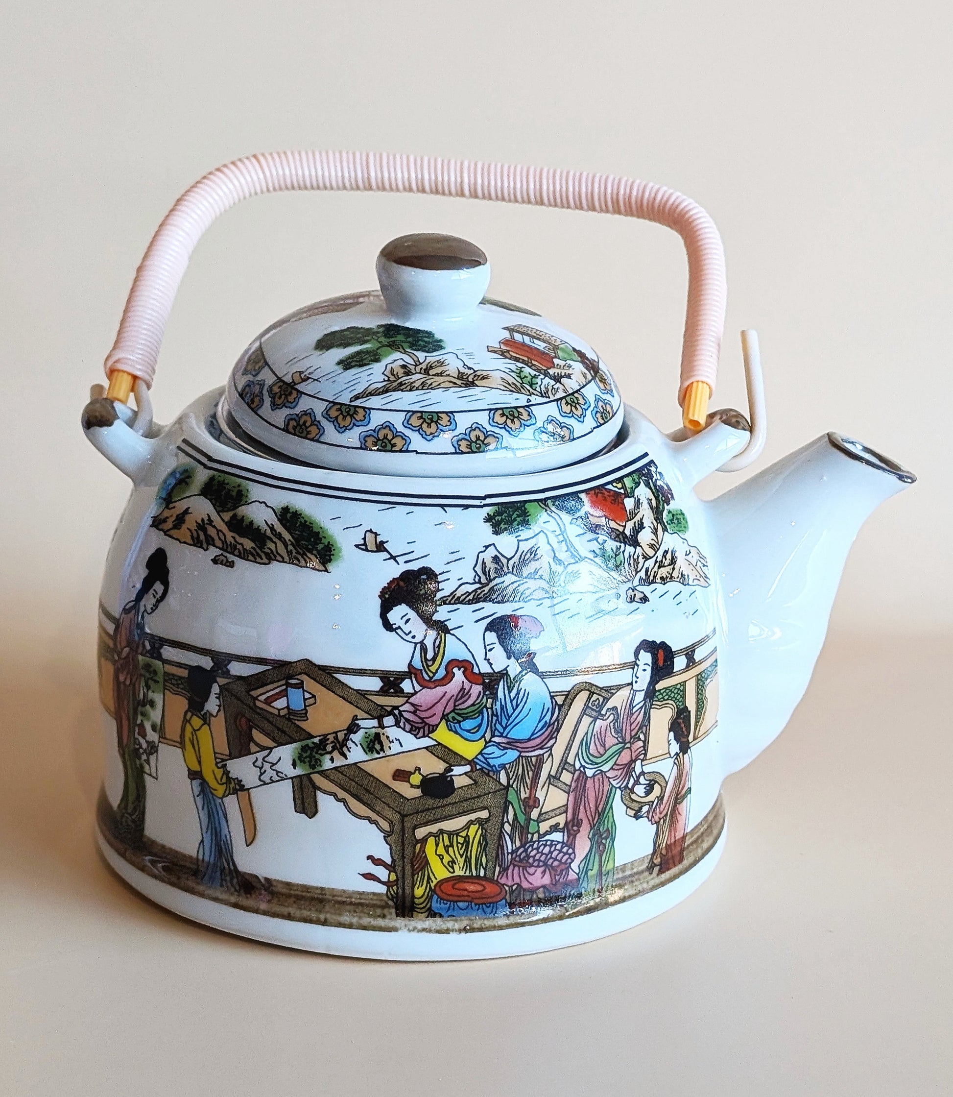 Decorative teapot with colorful scenes on a plain background