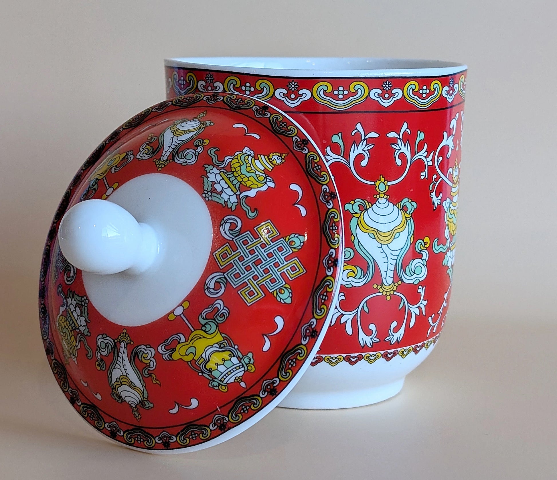 Decorative ceramic jar with a red lid featuring intricate patterns on a beige background