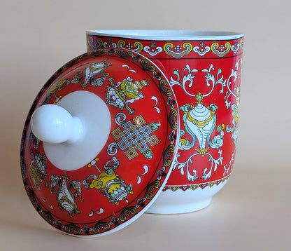 Decorative ceramic jar with a red lid featuring intricate patterns on a beige background