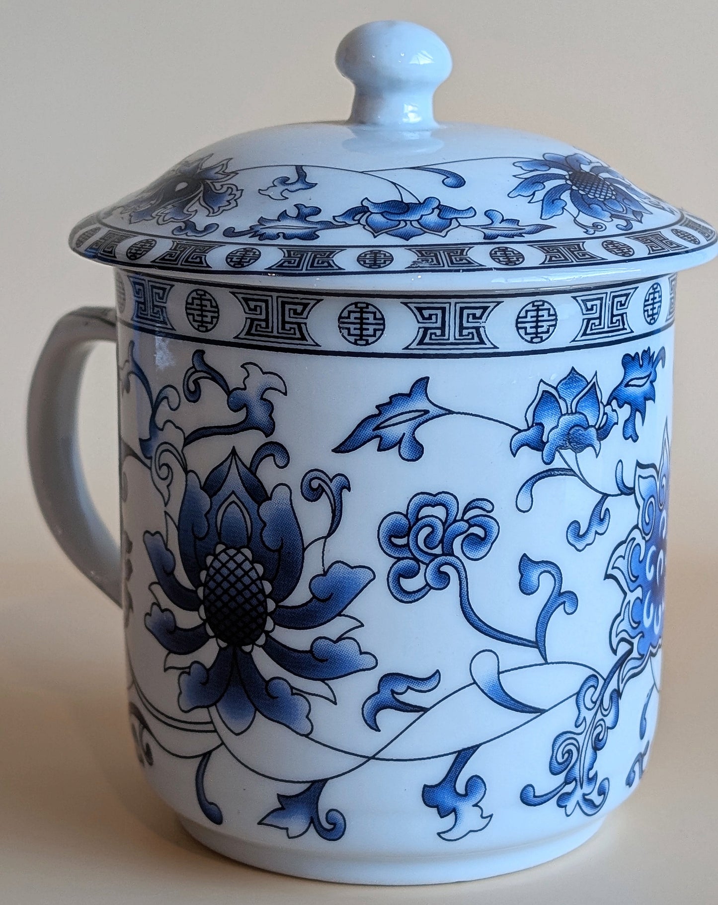 White ceramic mug with blue floral patterns on a beige background