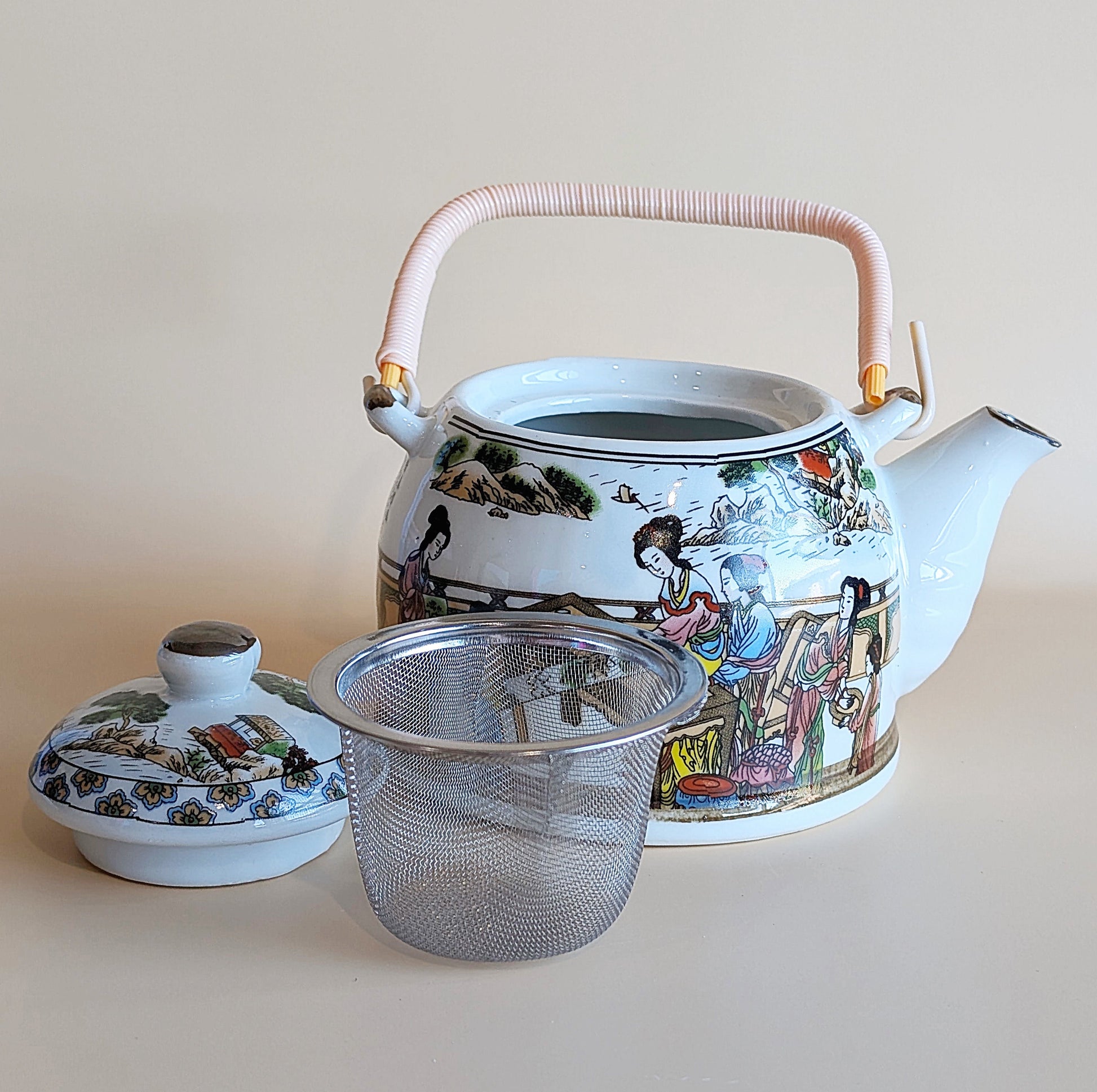 Decorative teapot with a lid and mesh strainer on a light background