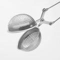 The Easy Grip & Steep Infuser by My Store is a stainless steel tea infuser with a spherical design, featuring two perforated hemispheres connected by a hinge. This dishwasher safe device has scissor-like handles for easy opening and closing, designed for steeping loose leaf tea in hot water.